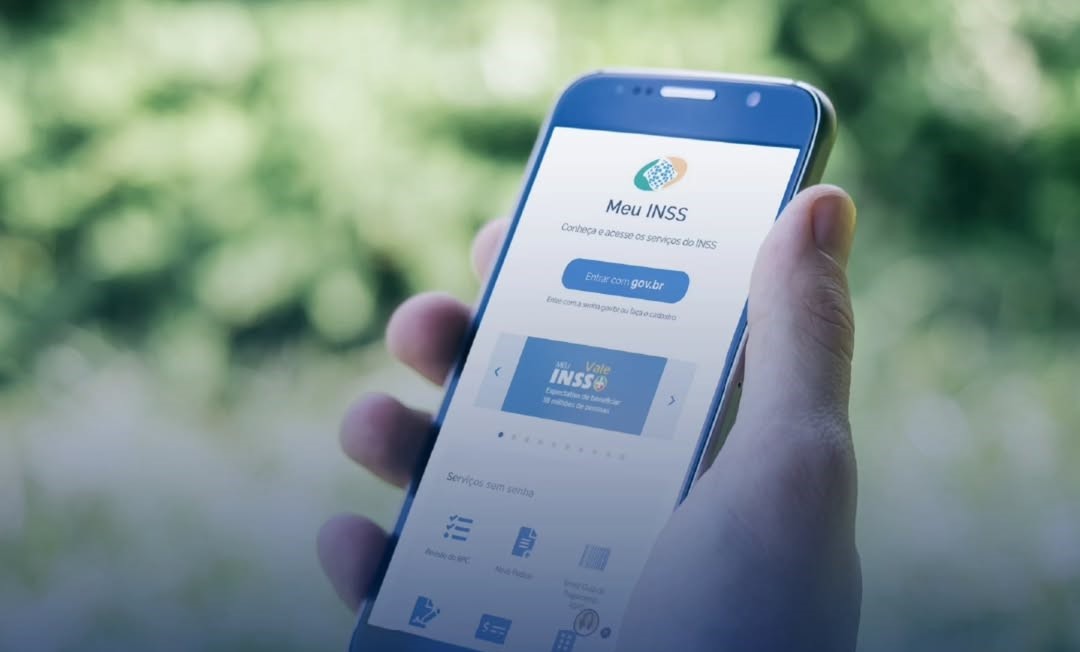 Pessoa segura um smartphone com a tela aberta no aplicativo Meu INSS, oferecendo acesso a serviços do INSS online.