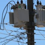 Transformador elétrico em poste, cercado por fios. Equipamento essencial para distribuição de energia elétrica urbana.