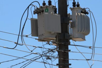 Transformador elétrico em poste, cercado por fios. Equipamento essencial para distribuição de energia elétrica urbana.