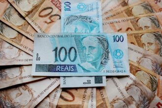 Notas de real brasileiro espalhadas, com destaque para cédulas de 50 e 100 reais, simbolizando economia e finanças.