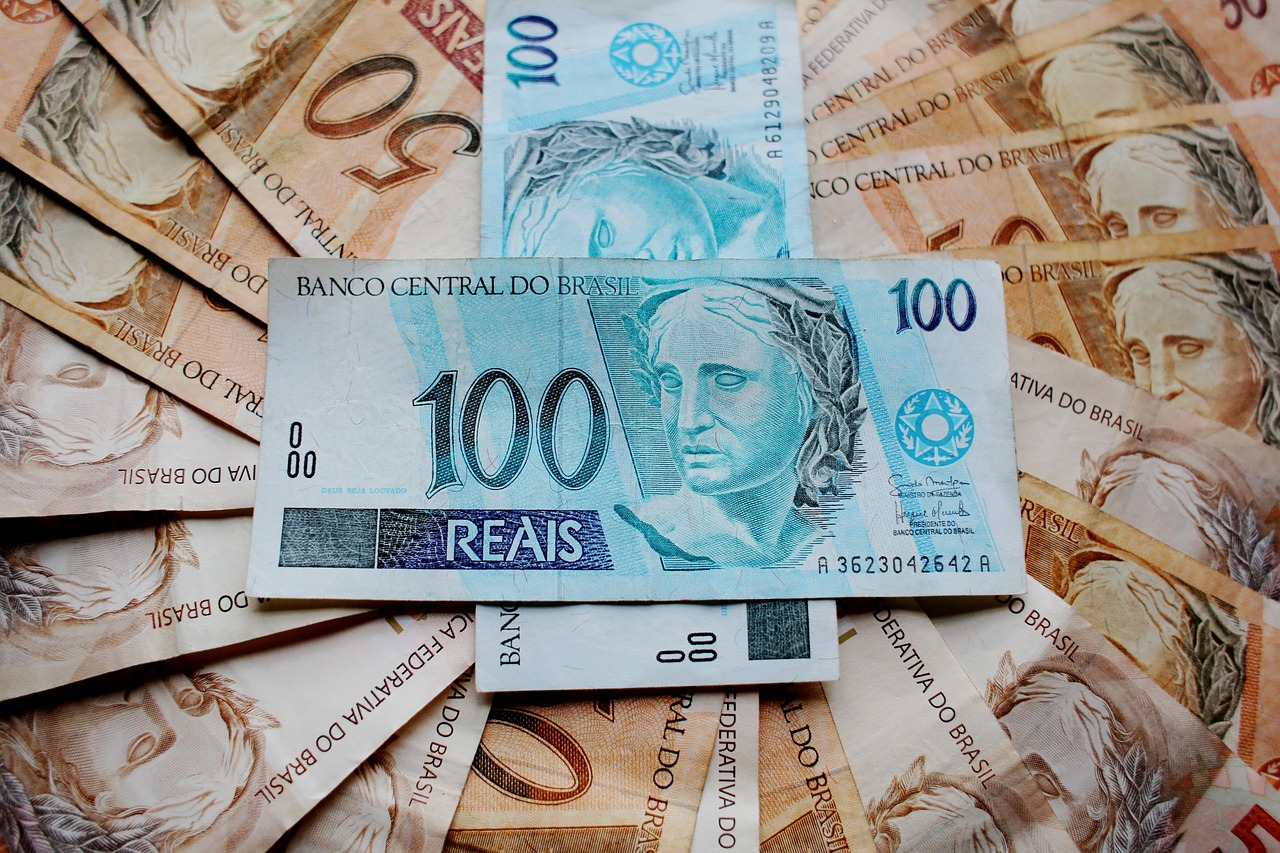 Notas de real brasileiro espalhadas, com destaque para cédulas de 50 e 100 reais, simbolizando economia e finanças.