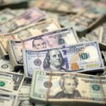 Pilhas de cédulas de dólar americano, destacando notas de 100, 20 e 5 dólares, simbolizando riqueza e finanças.