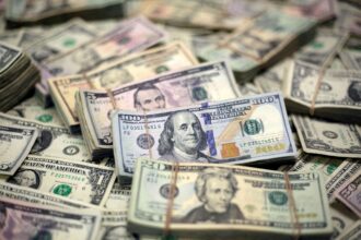 Pilhas de cédulas de dólar americano, destacando notas de 100, 20 e 5 dólares, simbolizando riqueza e finanças.