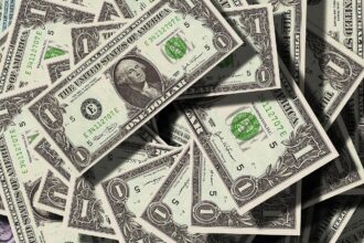 Notas de um dólar dos Estados Unidos sobrepostas, destacando o retrato de George Washington e detalhes em verde.