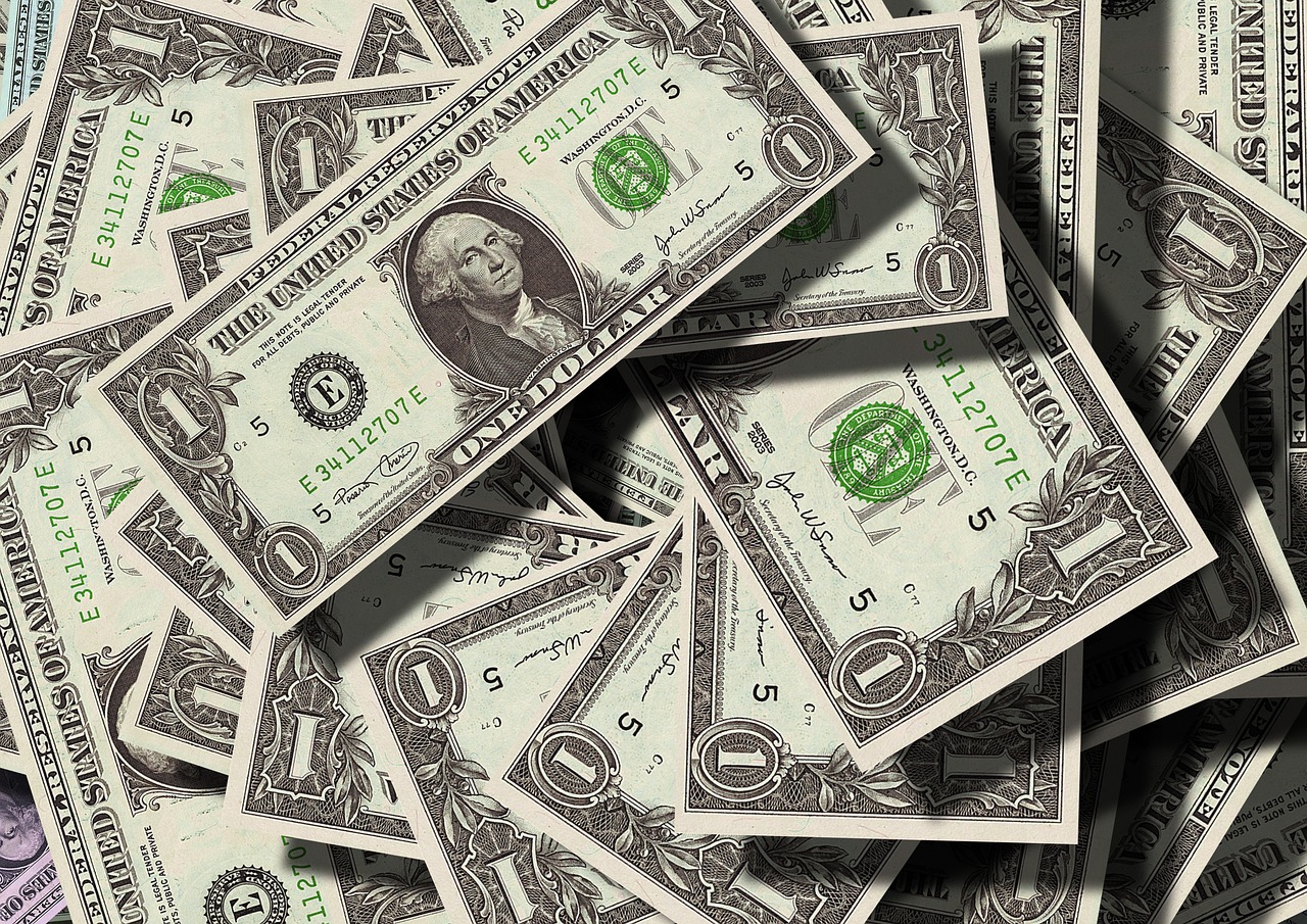 Notas de um dólar dos Estados Unidos sobrepostas, destacando o retrato de George Washington e detalhes em verde.