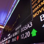 Painel digital de cotações da bolsa de valores com gráficos de ações e indicadores econômicos em destaque.