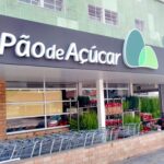 Fachada de supermercado Pão de Açúcar com carrinhos de compras e plantas na entrada, destacando compras e natureza.