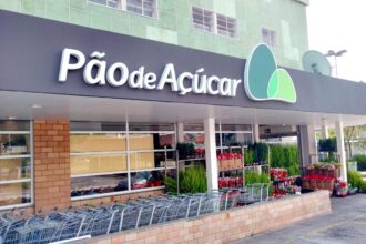 Fachada de supermercado Pão de Açúcar com carrinhos de compras e plantas na entrada, destacando compras e natureza.