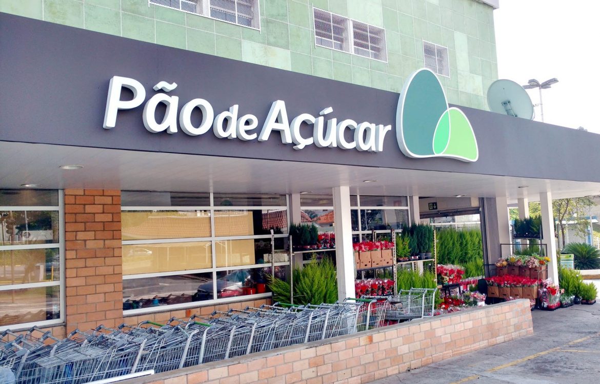 Fachada de supermercado Pão de Açúcar com carrinhos de compras e plantas na entrada, destacando compras e natureza.
