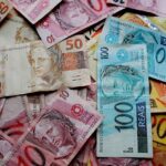 Notas de real brasileiro espalhadas, incluindo cédulas de 10, 50 e 100 reais, destacando economia e finanças.