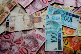 Notas de real brasileiro espalhadas, incluindo cédulas de 10, 50 e 100 reais, destacando economia e finanças.