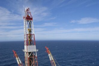 Plataforma de petróleo offshore em mar aberto com heliponto, gruas e estrutura complexa; destaque para exploração marítima.