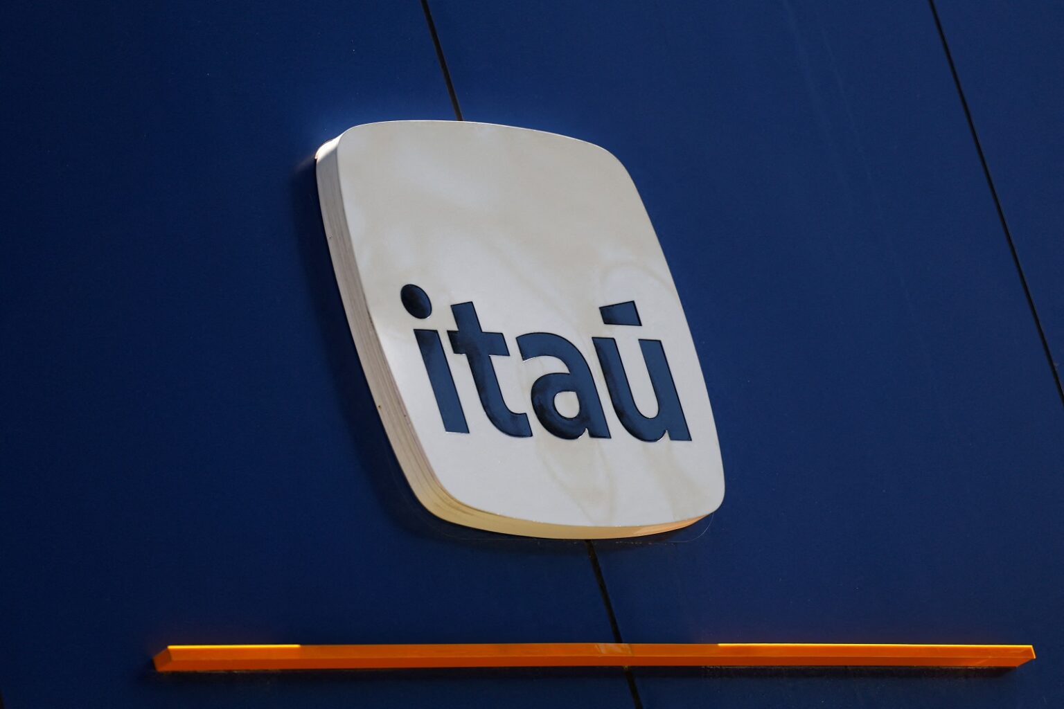 Logotipo do Itaú em fachada azul, destacando a identidade visual do banco com letras brancas em fundo estilizado.