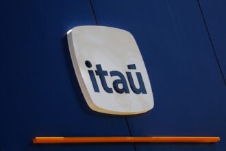 Logotipo do Itaú em fachada azul, destacando a identidade visual do banco com letras brancas em fundo estilizado.