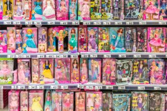 Prateleira repleta de bonecas diversas em caixas coloridas, incluindo modelos de princesas e moda, em uma loja de brinquedos.