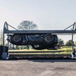 Carro preto em estacionamento elevado, exibido de lado, com árvores ao fundo. Destaque para design inovador e moderno.