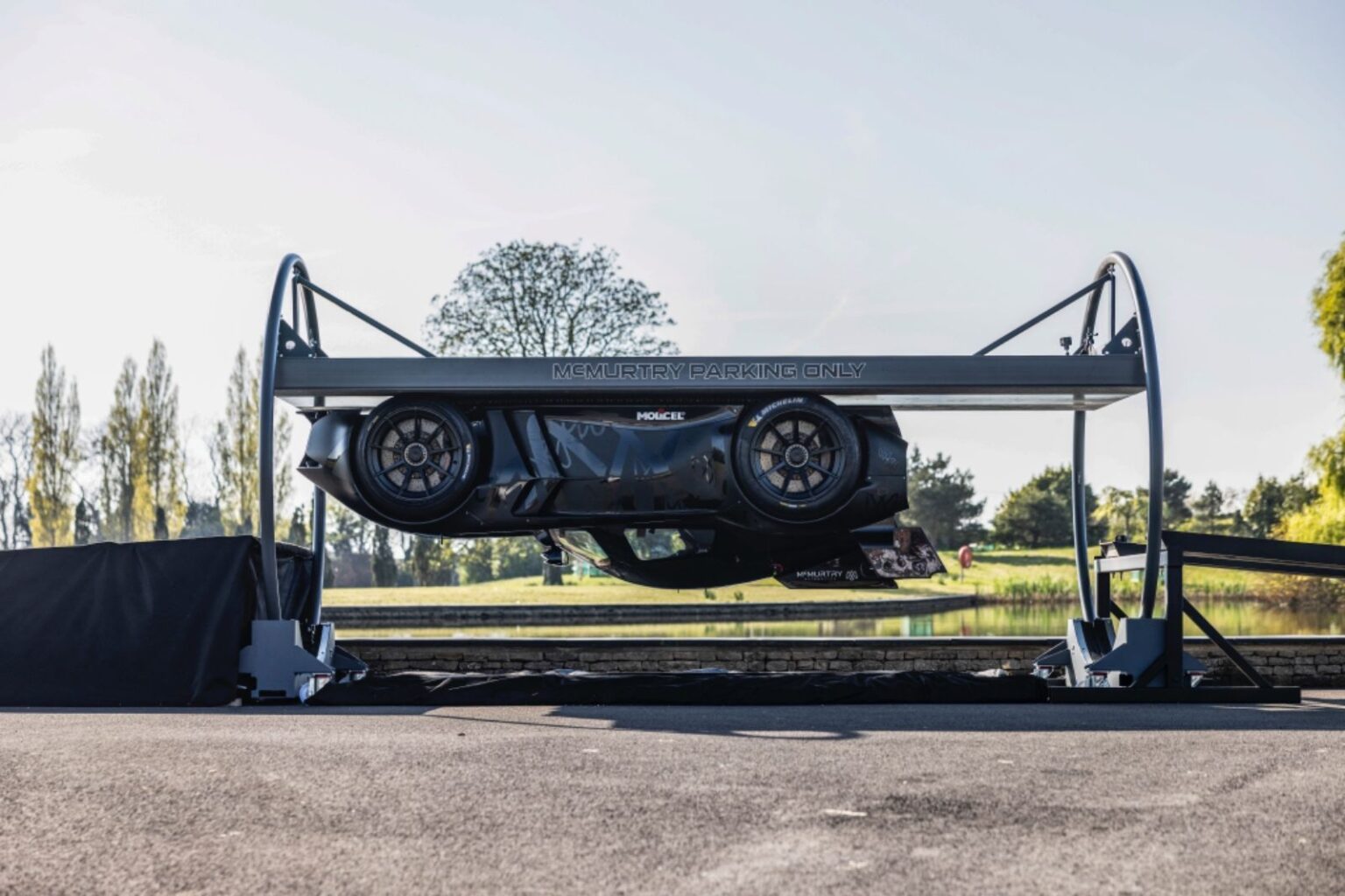 Carro preto em estacionamento elevado, exibido de lado, com árvores ao fundo. Destaque para design inovador e moderno.