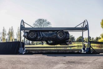 Carro preto em estacionamento elevado, exibido de lado, com árvores ao fundo. Destaque para design inovador e moderno.