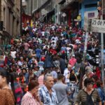 Multidão movimenta a Rua 25 de Março, em São Paulo, em um dia de compras, com barracas e lojas lotadas ao fundo.