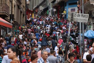Multidão movimenta a Rua 25 de Março, em São Paulo, em um dia de compras, com barracas e lojas lotadas ao fundo.