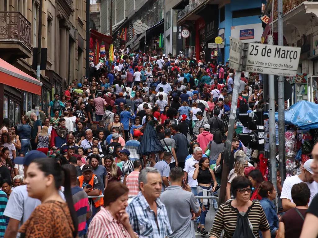 Multidão movimenta a Rua 25 de Março, em São Paulo, em um dia de compras, com barracas e lojas lotadas ao fundo.
