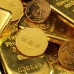 Barras e moedas de ouro brilhando, destacando riqueza e investimento seguro. Ideal para temas sobre finanças e economia.