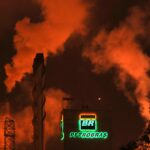 Fumaça laranja sobe de uma refinaria da Petrobras à noite, destacando o logotipo iluminado em meio à poluição industrial.