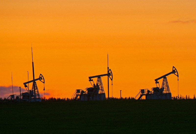 Bombas de petróleo operando em campo ao pôr do sol, realçando a indústria de energia em um cenário de céu alaranjado.