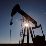 Bomba de petróleo operando ao ar livre com o sol ao fundo, destacando a extração de recursos naturais.