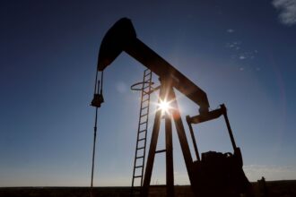 Bomba de petróleo operando ao ar livre com o sol ao fundo, destacando a extração de recursos naturais.