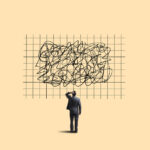 Homem de negócios confuso observa quadro com rabiscos desordenados, simbolizando complexidade e desafios no trabalho.