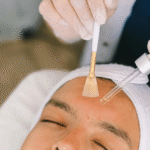 Tratamento facial em spa: pessoa com olhos fechados, aplicação de serum com pincel e conta-gotas para cuidados com a pele.