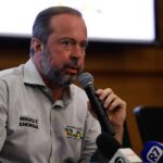 Homem segura microfone durante coletiva de imprensa sobre tema de energia, com camisas identificando Minas e Energia.