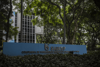 Entrada da Sabesp em São Paulo, cercada por árvores. Fachada moderna com placa azul destacando o nome da companhia.