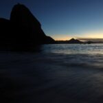 Pôr do sol no Rio de Janeiro, com o Pão de Açúcar em silhueta e o mar refletindo a luz suave do entardecer.