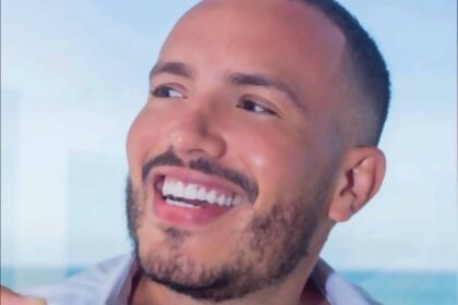 Morador da Santa Cecília é suspeito de aplicar golpes em série Um homem sorridente segurando uma xícara de café. Ele tem cabelo curto e barba bem aparada. O fundo mostra uma vista para o mar, sugerindo um ambiente relaxante. O homem está usando uma camisa branca aberta, revelando parte do peito.