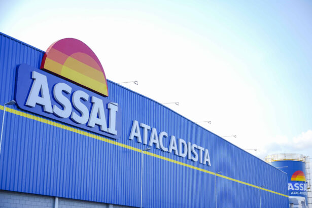 Fachada azul do supermercado Assaí Atacadista com o logotipo colorido em destaque. Céu claro ao fundo.
