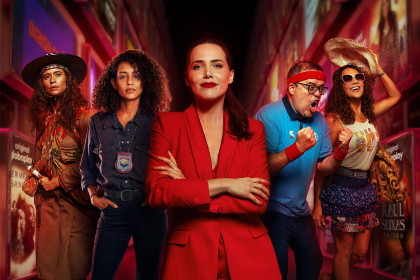 Globoplay adota novas estratégias para concorrer com a Netflix Cinco pessoas em pé em uma rua iluminada à noite. No centro, mulher de terno vermelho com braços cruzados. Ao redor, pessoas com roupas casuais e estilos variados. Texto
