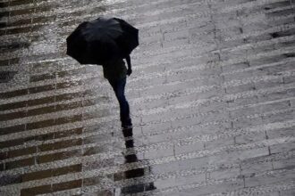 Pedestre se protege da chuva  na região central da cidade de São Paulo, em março deste ano
