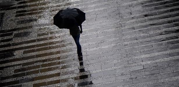 Pedestre se protege da chuva  na região central da cidade de São Paulo, em março deste ano