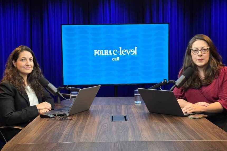 C-Level Call não ocorrerá nesta quinta-feira, 18 de dezembro Duas mulheres sentadas em frente a uma mesa de madeira em estúdio com fundo azul escuro. Ambas usam laptops e falam em microfones de mesa. Ao fundo, tela exibe logo