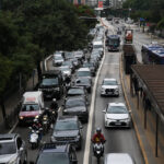 Detran de SP remove prova de baliza para obtenção da CNH Veículos e motocicletas congestionados em duas faixas da via expressa durante o dia. Ônibus circulam na faixa exclusiva ao lado direito, com ponto de ônibus visível. Árvores e edifícios cercam a via.