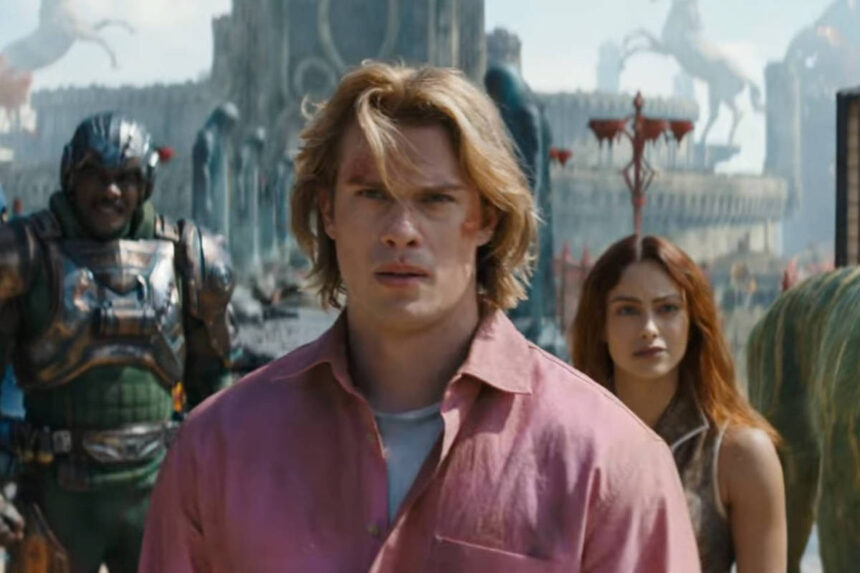 Homem de cabelo loiro e camisa rosa está no centro da imagem, com mulher de cabelo longo e escuro atrás dele à direita. À esquerda, dois personagens com armaduras futuristas e um tigre com listras verdes e amarelas está à direita. Cenário ao fundo inclui estruturas e estátuas em ambiente aberto.